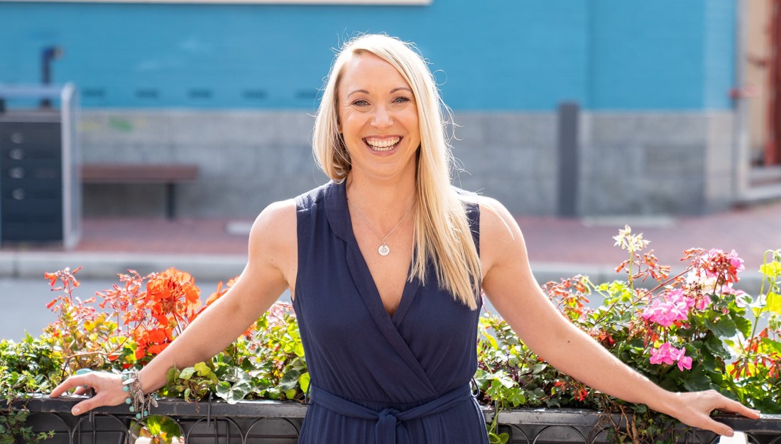 Blonde woman standing on front of flowers