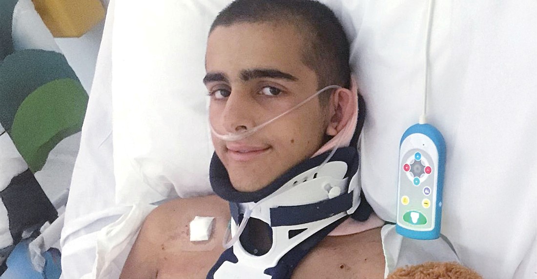 Young man in hospital, with a neck brace on, looking at the camera.