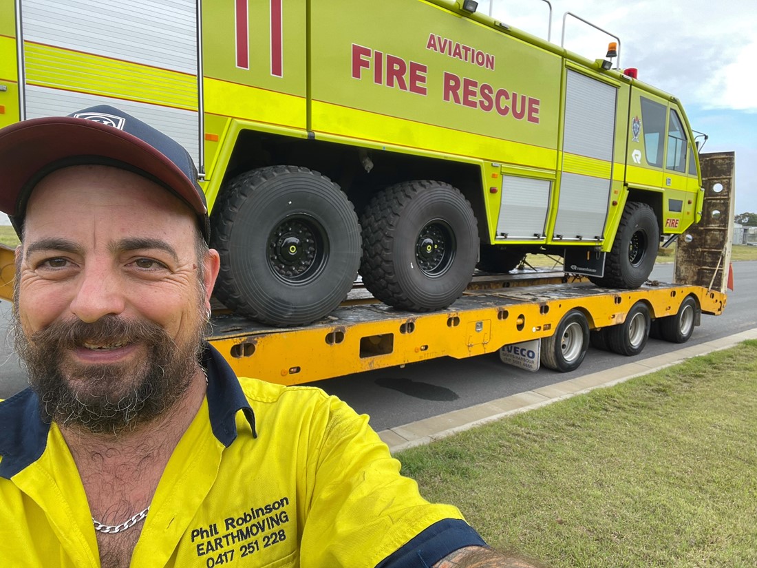 Eno in yellow work uniform with truck in background