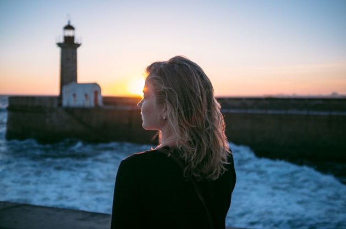 Girl overlooking ocean with lighthouse on her right