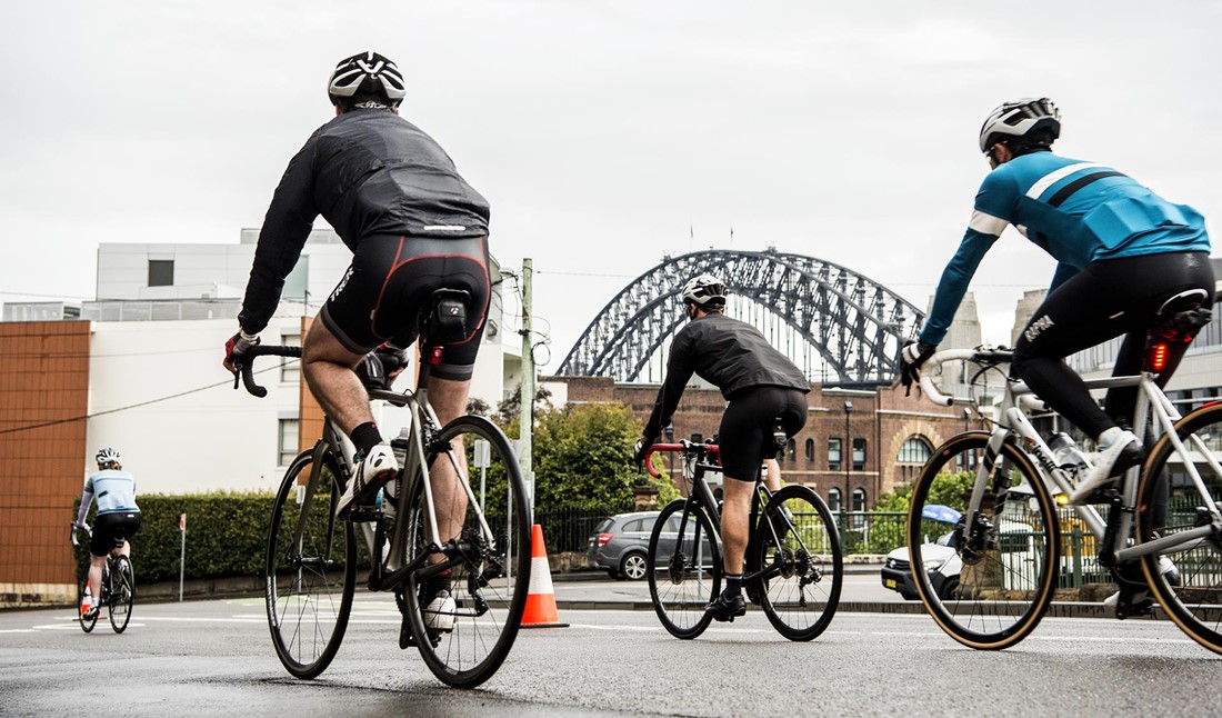 Four cyclists competing in the "Spring Cycle" race, with the Sydney Harbour Bridge in the background 