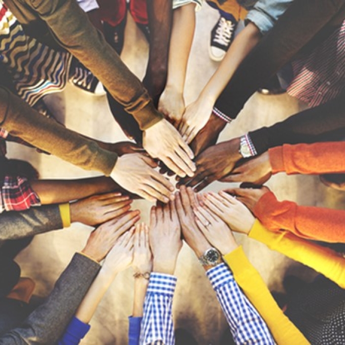 A group of people standing in a circle with their hands stacked together in the center