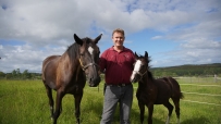 man standing with two horses