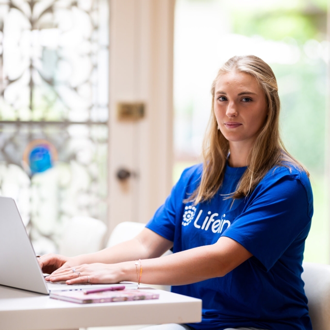 Crisis Supporter – Woman wearing a Lifeline branded shirt sitting at a table