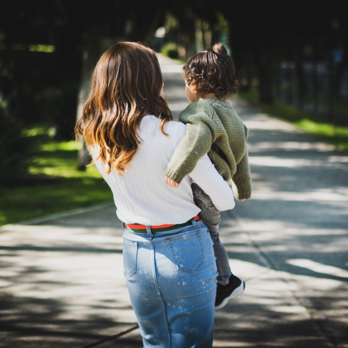 Mother and child walking through a park with their backs to the camera