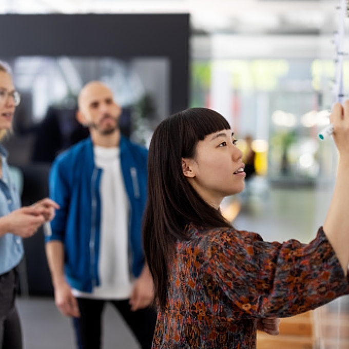 Three office workers standing in front of a whiteboard