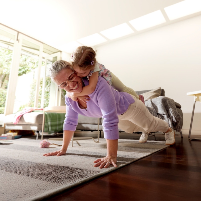 Smiling mother doing push up with child on her back