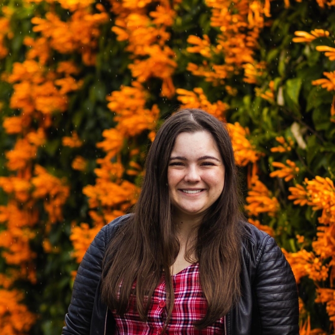 woman smiling, wearing a plaid dress and leather jacket